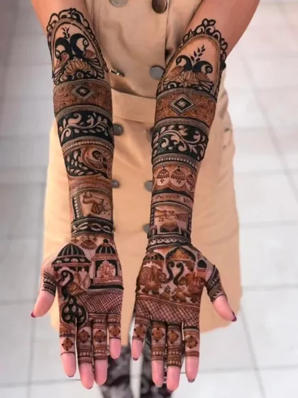 A classic bridal design featuring bands of peacocks, elephants, and temple bells, covering the arms from fingertips to elbow.