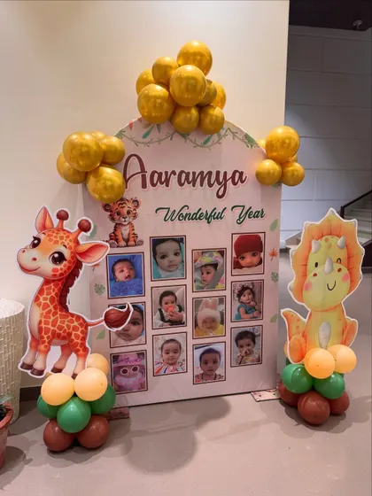 A personalized "Wonderful Year" photo board from a jungle-themed party, showcasing the baby's monthly pictures alongside cute giraffe and dinosaur cutouts.