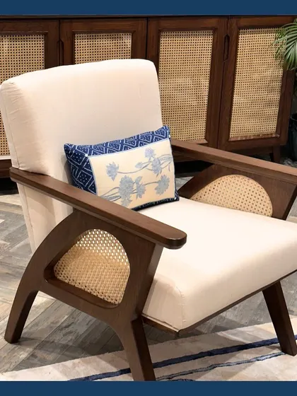 Our modern lounge chair with cane details, upholstered in natural Khadi and accented with a hand-embroidered indigo cushion. This piece blends traditional materials with a contemporary form.