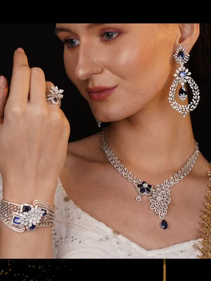 A model wearing a stunning sapphire and diamond jewellery set. The deep blue of the sapphires provides a regal contrast to the brilliant white diamonds and the elegant white attire.