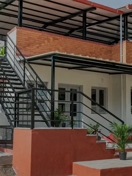 The L-shaped staircase is a key feature of the Anganwadi, combining a concrete base with sleek metal treads. It adds a unique scale to the building and provides access to the rooftop play area, turning a simple circulation element into a point of interest.
