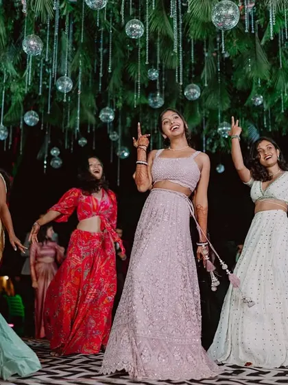 The bridesmaids own the dance floor under the canopy of disco balls and greenery.