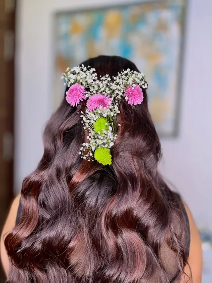 A half-up hairstyle with soft waves, adorned with fresh flowers. This is a versatile look that works for many different events.