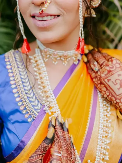 A detailed close-up of the bride's attire, focusing on her jewelry and the intricate henna design on her hand.