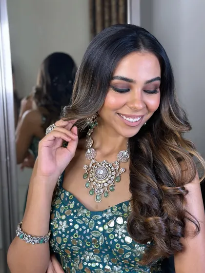 A close-up in front of a mirror, showing the beautiful details of the makeup and jewelry. The look is polished and perfect.
