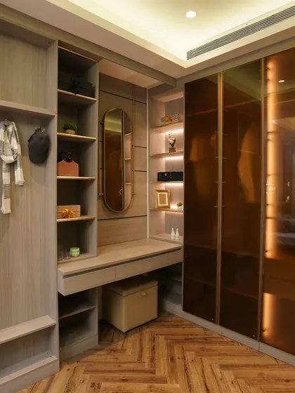 A spacious walk-in closet with a mix of open and closed storage. The vanity is neatly integrated into the unit, with a large mirror and ample lighting.