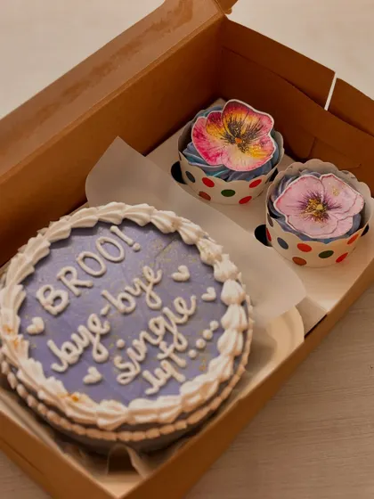 Another look at the "Broo! bye-bye single life..." bento cake combo, highlighting the pretty edible flower designs on the cupcakes which contrast beautifully with the purple cake.