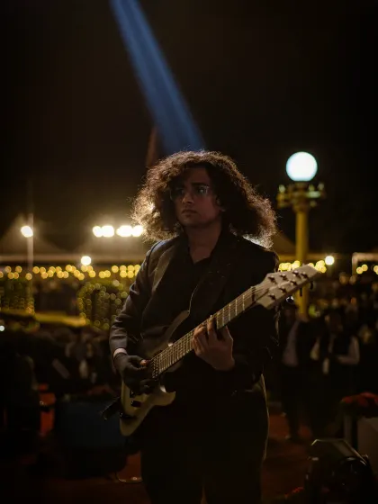 Rishi Singh plays lead guitar under the night lights in a portrait from his time performing with us.