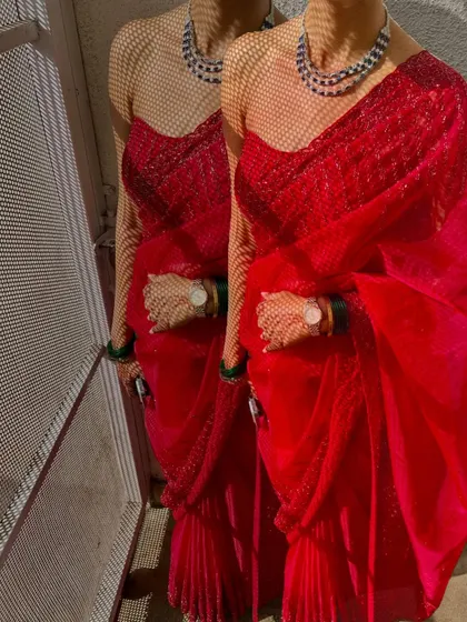 An artistic shot of the red saree, playing with shadows and light to highlight the texture of the fabric.