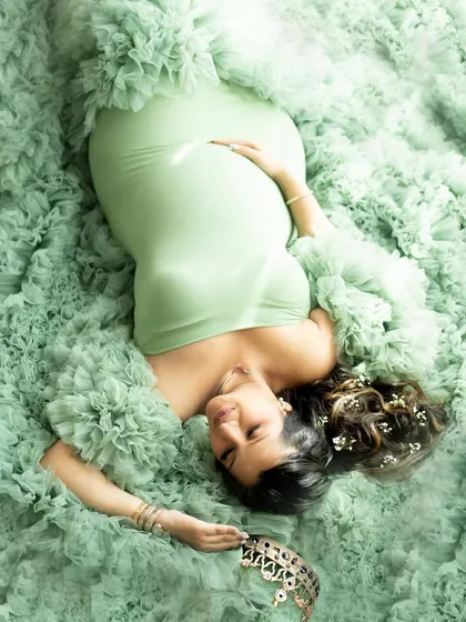 An artistic overhead shot of a mother-to-be in a beautiful green gown, holding a crown to symbolize the queen she is.