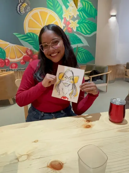 A happy guest with her caricature, enjoying the artistic experience at the cafe.