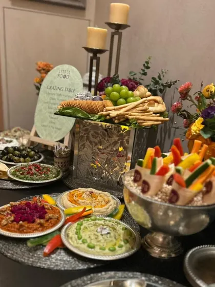 A Mediterranean-inspired grazing table featuring a colorful assortment of dips like hummus and muhammara, served with olives, fresh vegetables, and breadsticks. This setup is perfect for a light and healthy yet flavorful party spread.
