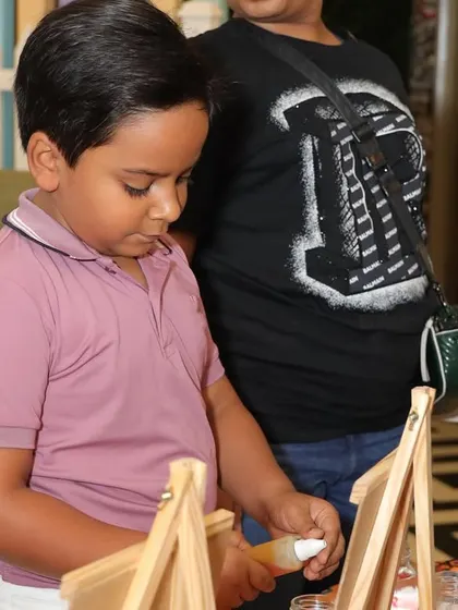 A boy carefully works on a craft project during a birthday party.