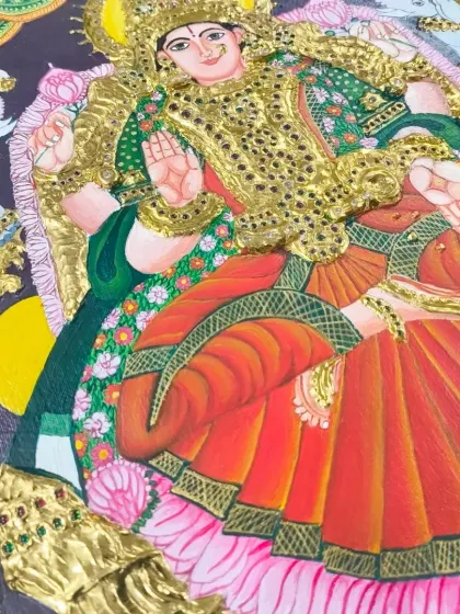 A close-up of a finished Tanjore painting of Goddess Lakshmi, adorned with shimmering stones and 24K gold foil. This piece is a testament to the student's dedication and skill.
