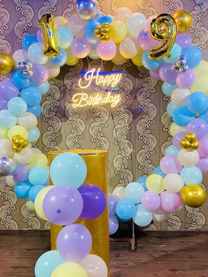 A 19th birthday celebration with a pastel-colored balloon ring and a "Happy Birthday" neon sign.
