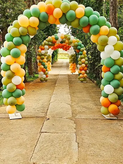 A series of balloon arches creates a grand and festive entrance walkway for a large outdoor jungle-themed party.