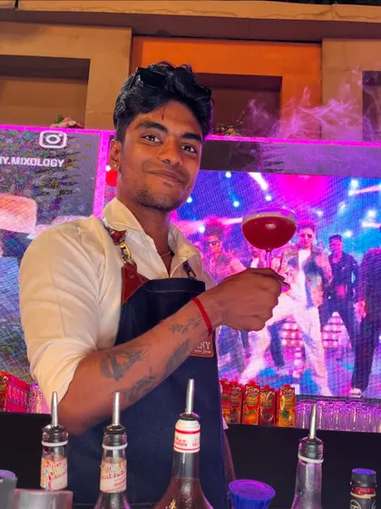 The smoky 'Bubble Pop' cocktail presented with a vibrant, colorful LED screen in the background, perfect for a sangeet or reception.