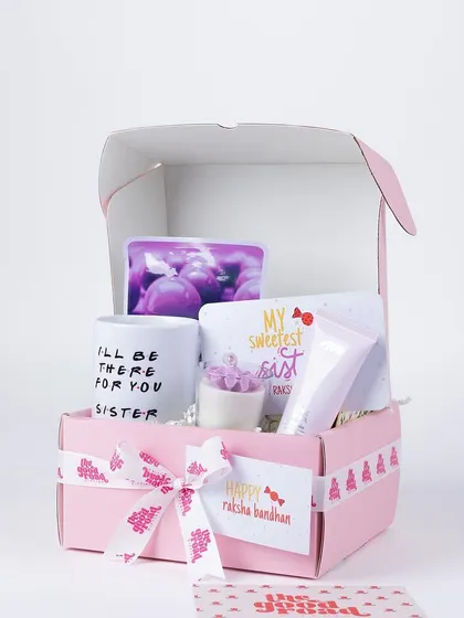 A pretty pink Rakhi hamper for a sister, with a "I'll be there for you" mug, a scented candle, and other pampering goodies.