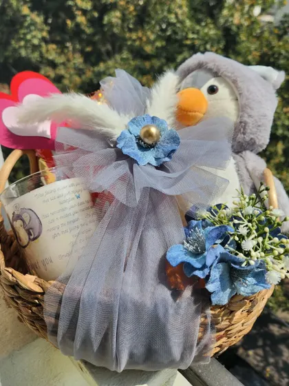 A cute and cuddly penguin soft toy paired with a scented candle in a rustic basket, making for a sweet and simple Teddy Day gift.