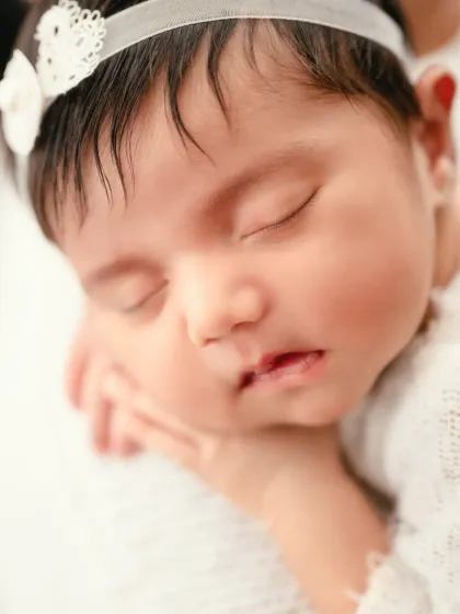 A close-up of a sleeping newborn's face, capturing the delicate features and peacefulness of the first few weeks of life.