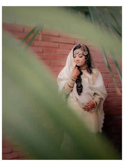 Another artistic shot of Lubna, peeking through palm leaves, which adds a natural and intimate frame to her portrait.