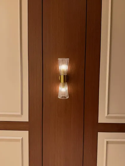 A close-up of a classic wall sconce set against dark wood and light-colored paneling. This kind of accent lighting adds a layer of sophistication to the entrance area.