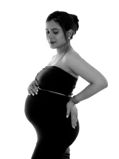 A beautiful and serene black and white portrait. The simple styling and clean background put all the focus on the mother-to-be's peaceful expression and her beautiful bump.