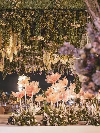 A wide shot of the outdoor venue, showing the expansive floral ceiling installation over the main stage. The design was intended to feel like a magical, blooming garden suspended in the air.