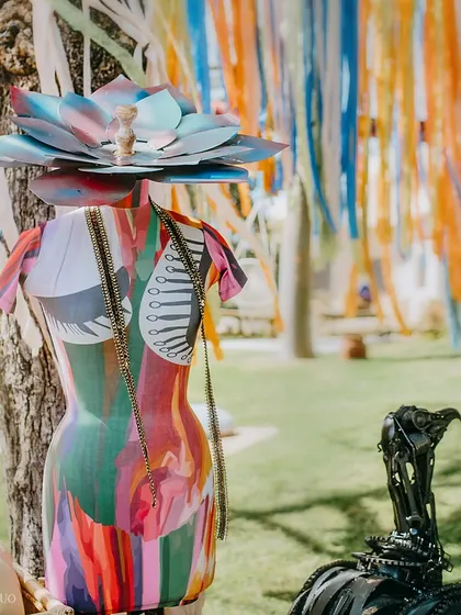 A painted mannequin torso, adorned with a lotus headpiece and chains, stands by a tree, contributing to the eclectic and artistic vibe of the event.