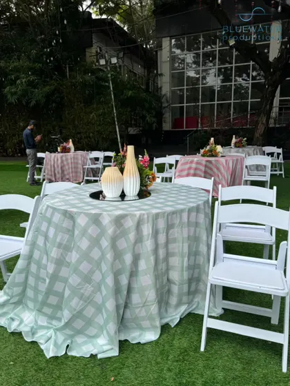 A mix of patterned tablecloths in shades of green and pink adds a whimsical and eclectic touch to the lawn party.