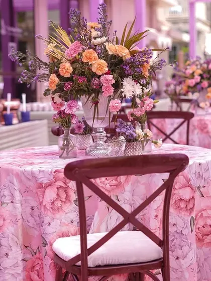 The guest tables were dressed in floral-printed tablecloths and topped with beautiful centerpieces of pastel blooms. The wooden cross-back chairs added a touch of rustic elegance.