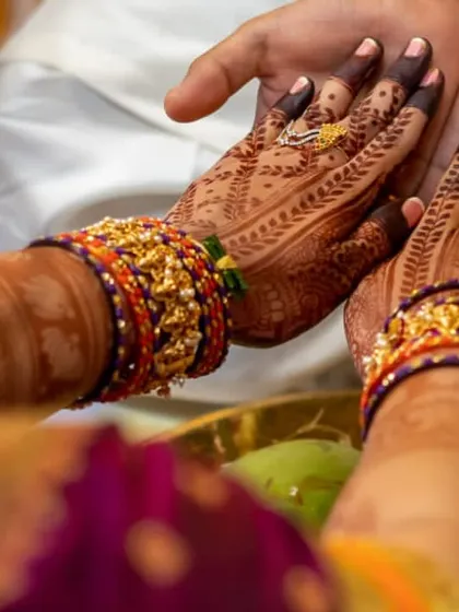 A moment from a wedding ritual, showcasing the bride's beautifully stained hands. The intricate patterns on her palms are clearly visible, a result of proper aftercare.