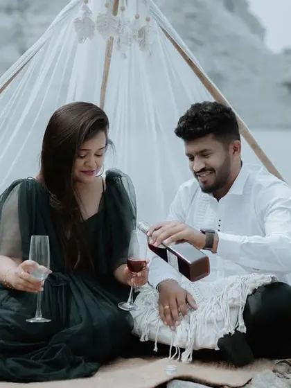 A romantic moment from a styled pre-wedding shoot, with the groom pouring wine for the bride by a serene lake.