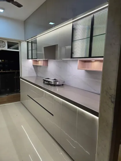 This linear kitchen showcases a beautiful high-gloss, lacquered finish that reflects light and creates a sense of space. We've incorporated fluted glass cabinets and integrated LED strip lighting under the counter for both task lighting and ambiance.