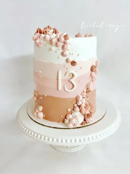 Simple, chic, and elegant. This cake for a 13th birthday features a beautiful ombre buttercream effect in shades of pink, decorated with delicate piping and pearls.