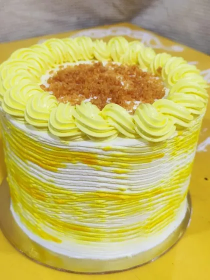 This is a tall version of my butterscotch cake. It features textured yellow and white buttercream and is topped with a sprinkle of butterscotch crunch.