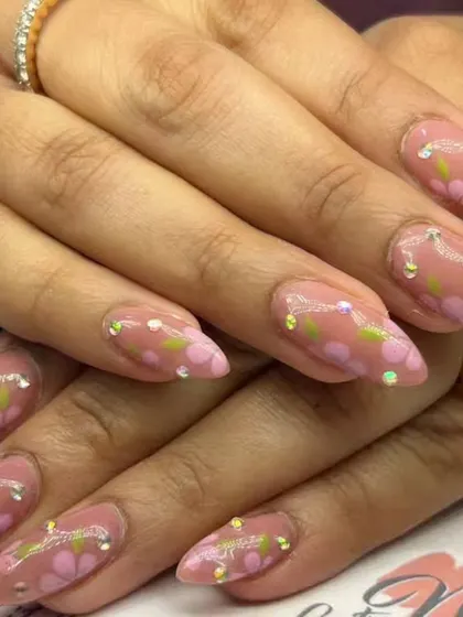A lovely floral design with hand-painted pink flowers and green leaves on a nude base, accented with tiny sparkling rhinestones.