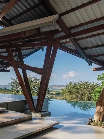 Another view of the pool and verandah at the Lateral Verandah House, where the unique timber supports create a forest-like rhythm within the architecture.