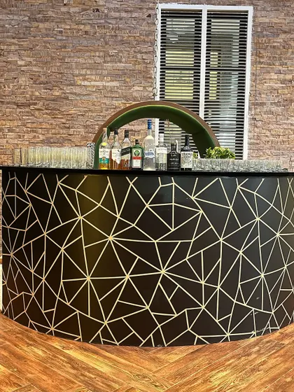 This curved bar features a striking black and gold geometric pattern. It's a contemporary design that adds a touch of modern sophistication to corporate events or stylish private parties.