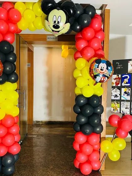 A Mickey Mouse themed balloon arch at the entrance of a party venue, welcoming guests to the celebration.