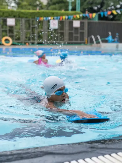 A young swimmer confidently practicing with a kickboard. This tool is invaluable for helping kids focus on their leg strength and body position.