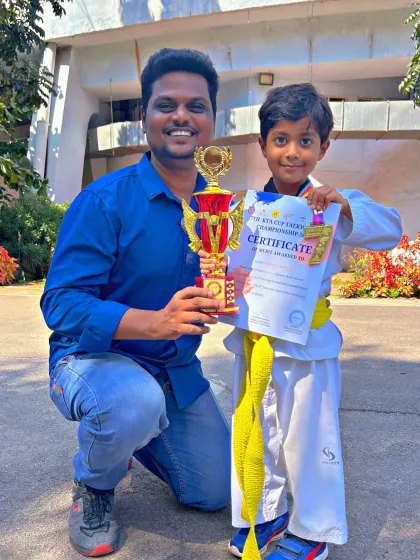 A beaming young student with his well-earned trophy and certificate, showcasing the success of our junior martial artists.