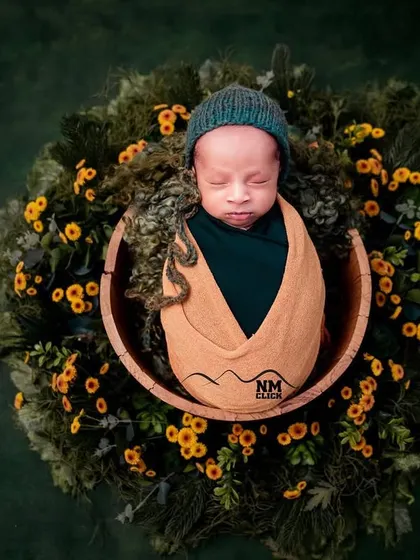 The earthy tones of this setup with a green wrap and floral wreath create a beautiful, nature-inspired newborn portrait.