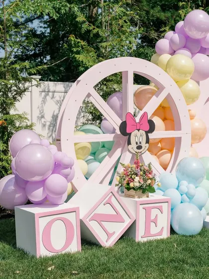 A close-up of the "ONE" blocks and the pink wheel prop, showcasing the charming details of the Disney-themed first birthday.