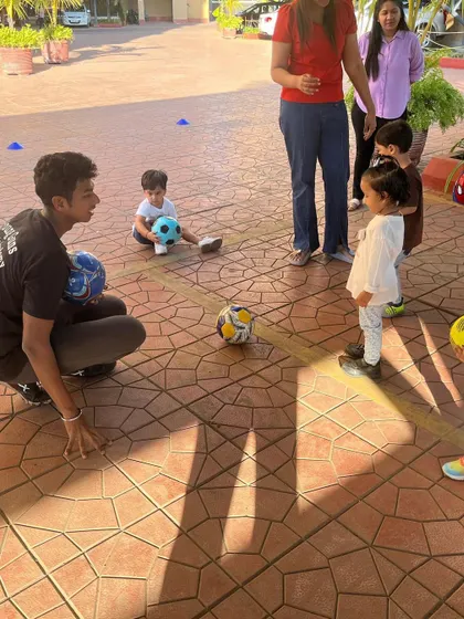 A coach interacts with a toddler during a football class. Our coaches are skilled at working with the youngest of players, making their first sports experience a positive one.