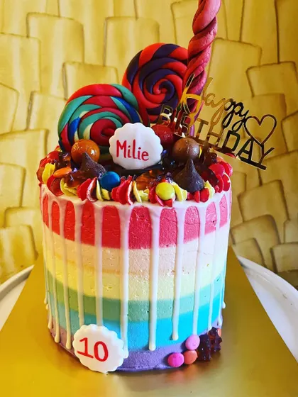 Let your imagination run wild with my custom themed cakes. This Candyland cake, made for a 10th birthday, is a vibrant example of my craft, featuring a rainbow-striped vanilla cake with blueberry compote, topped with a delightful collection of lollipops and candies.