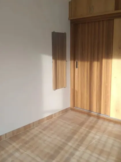 A bedroom with clean, white walls that make the wooden wardrobe and flooring stand out. Natural light enhances the fresh look of the new paint.