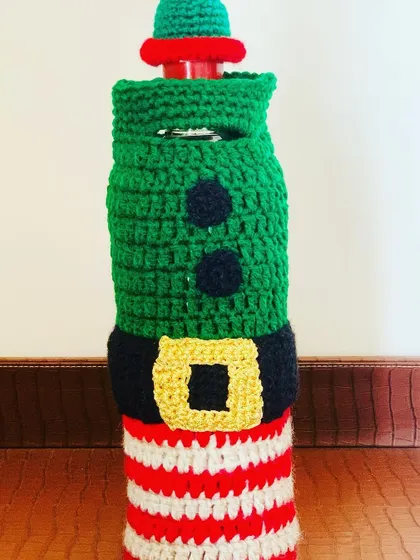 An elf-themed wine bottle cover, complete with striped pants, a belt, and a little hat. It's a whimsical way to present a bottle of wine.