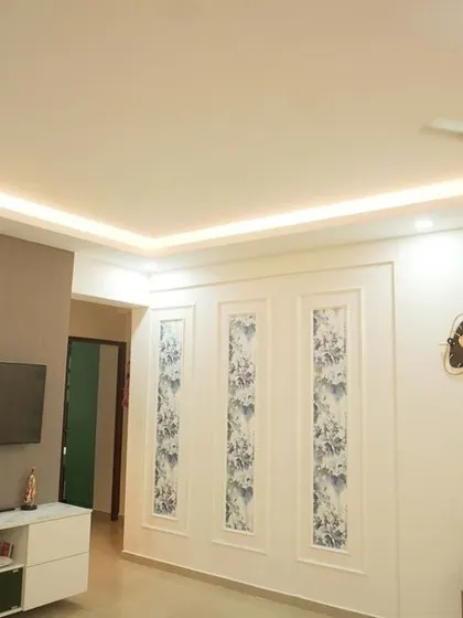 A wide view of a living area, showing how the TV unit and wall panels create a cohesive look. The space feels open and connected to the adjacent kitchen area.