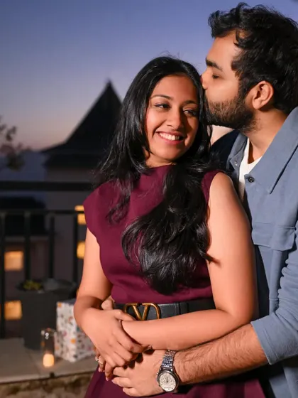 A happy and affectionate close-up, capturing her bright smile as he kisses her forehead. The twilight in the background adds to the romantic mood.